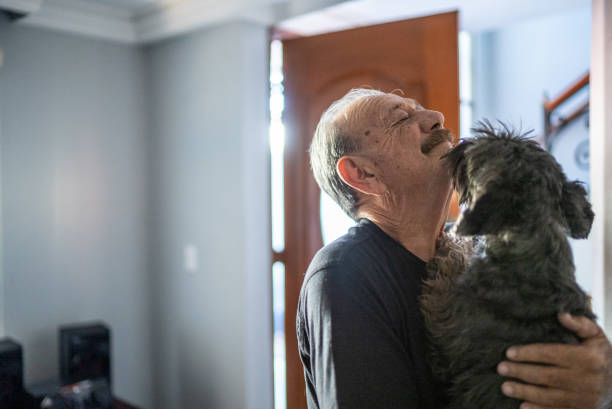 istock Senior man playing with dog at home 1486141570