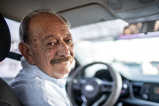 Portrait of senior man on the driver's seat of a car