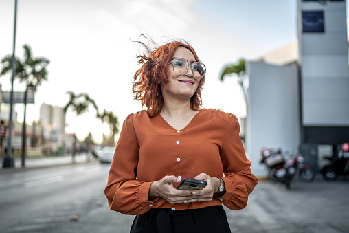 Mid adult woman using mobile phone while walking outdoors