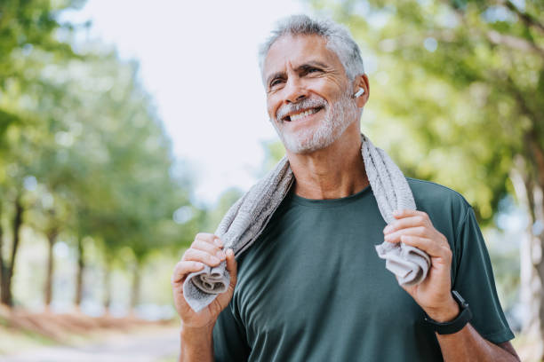 пожилой мужчина-бегун держит полотенце на шее - aging process morning outdoors horizontal стоковые фото и изображения