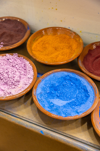 Colorful pigments in blue and yellow at Marrakech spice Souk with artisanal mosaic tile wall