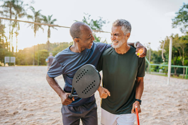 dos amigos mayores jugando al tenis de playa - senior adult relaxation exercise healthy lifestyle exercising fotografías e imágenes de stock