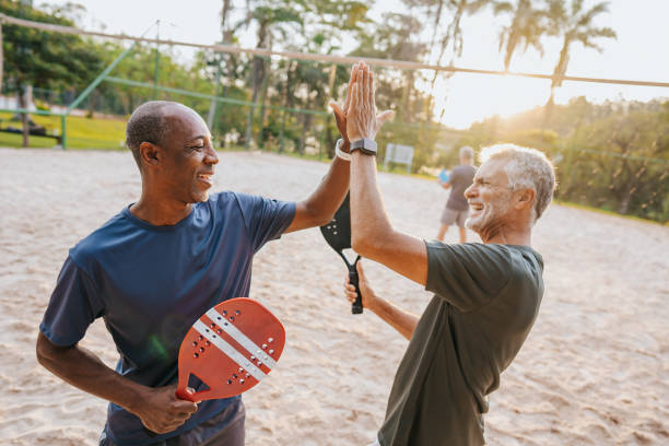 dwóch starszych przyjaciół grających w tenisa plażowego - tennis active seniors healthy lifestyle senior men zdjęcia i obrazy z banku zdjęć