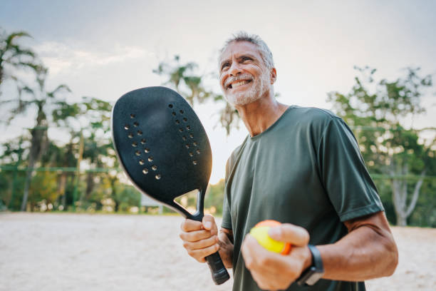 senior man playing beach tennis - tennis active seniors healthy lifestyle senior men imagens e fotografias de stock