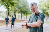 Senior man runner looking at smartwatch outdoor activity