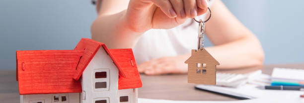 istock woman hand house key and house model on table 1486149927