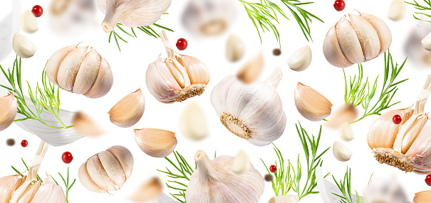 Flying Garlic with red and black pepper and herbs on light white background. Spicy and fragrant seasoning food for cooking. Creative food concept for design, advertising, menu and recipes. Pattern.