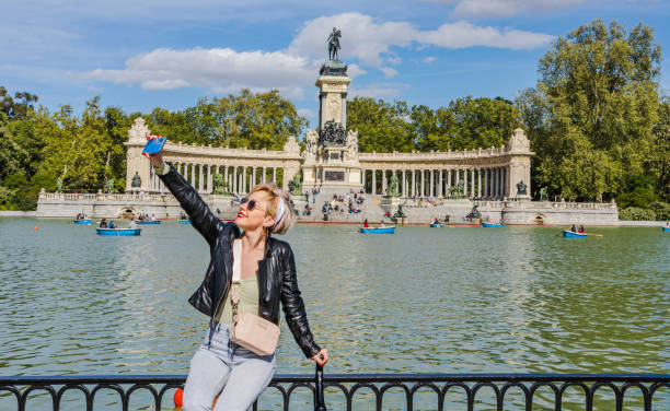 Woman taking a selfie in Buen Retiro Park in Madrid Cheerful woman taking a selfie in front of the lake and Alfonso XII Monument in the Buen Retiro Park (Parque del Buen Retiro) in Madrid, Spain selfie madrid photos stock pictures, royalty-free photos & images