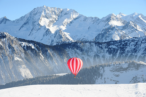 Hot air balloon on the slopes of Courchevel ski resort by winter with Mont Blanc mountain behind