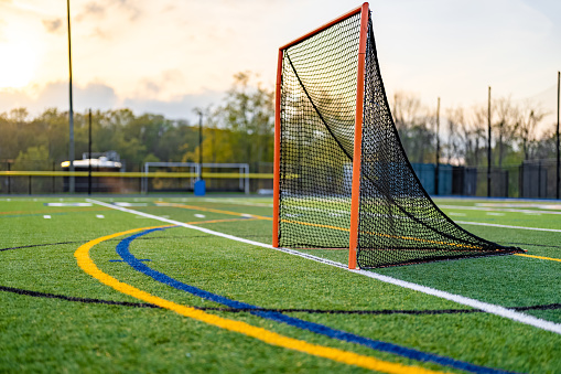 Late afternoon photo of a lacrosse goal on a synthetic turf field before a night game.