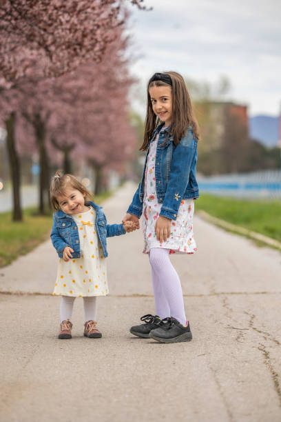 istock Sisters hold hands and pose in  public park 1486166715