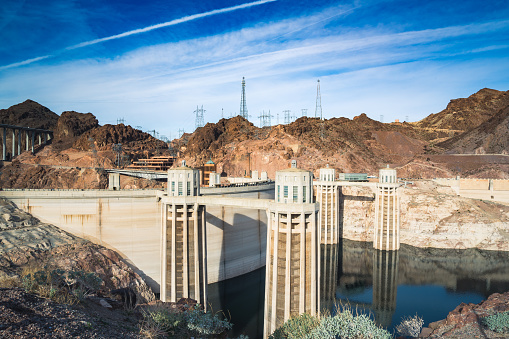 The Hoover Dam, a concrete arch-gravity dam on the Colorado River, sits at the Nevada-Arizona border. Finished in 1936, it measures 726 feet tall and spans 1,244 feet across the Black Canyon. Thousands of workers contributed to the dam's construction, which aimed to control floods, supply irrigation water, and produce hydroelectric power. Its power plant boasts a capacity exceeding 2,000 megawatts, providing electricity to millions in the Southwest. The Hoover Dam is renowned for its engineering and draws hordes of visitors every year. A feat of modern engineering and a popular tourist attraction, the Hoover Dam is an iconic American landmark.