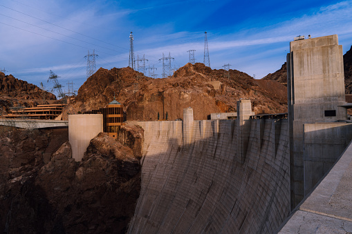 The Hoover Dam is a concrete arch-gravity dam located in the Black Canyon of the Colorado River, on the border between the U.S. states of Nevada and Arizona. Completed in 1936, it stands 726 feet tall and spans 1,244 feet across the canyon. The dam's construction required the labor of thousands of workers and its purpose was to control floods, generate hydroelectric power, and provide irrigation water to the surrounding areas. The dam's power plant has a capacity of over 2,000 megawatts and provides electricity to millions of people in the Southwest. The Hoover Dam is considered a marvel of modern engineering and a popular tourist attraction.