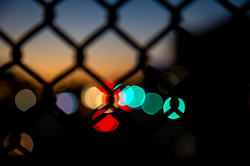 Intentionally out of focus foreground and background of traffic lights shot through a chain link fence resulting in bokeh