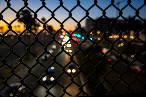 Traffic on Pacific Coast Highway shot through a foreground of an in focus  chain link fence