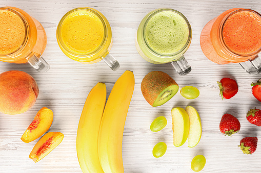 Many different tasty smoothies and ingredients on white wooden table, flat lay