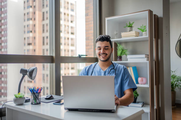 male nurse on telemedicine in his office - nurse doctor scrubs male imagens e fotografias de stock