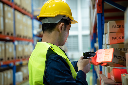 Warehouse worker scan box goods in inventory and check stock product. Transport logistic business shipping and delivery to customers through a freight forwarding company.
