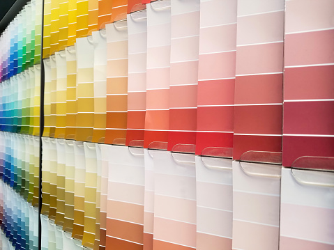Choosing the right paint from colorful Paint Sample Color Swatch. The pant Sample Charts in variety of colors are spread over the table, the image is full frame close-up of the various color swatch.