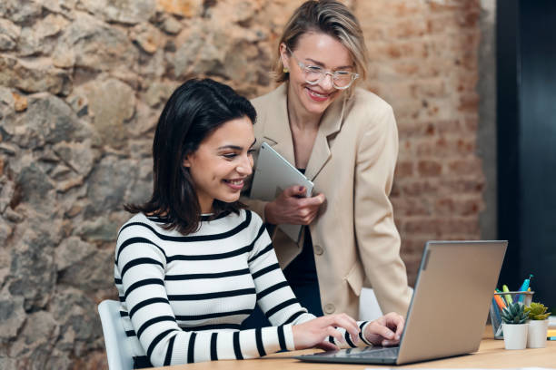 istock Two beautiful designer women working with laptop while choosing materials in digital tablet in the modern office. 1486177777