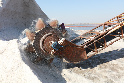 machine placing the harvested and washed salt on a conveyor belt. Salt production equipment, The equipment and salt stock of a salt plant