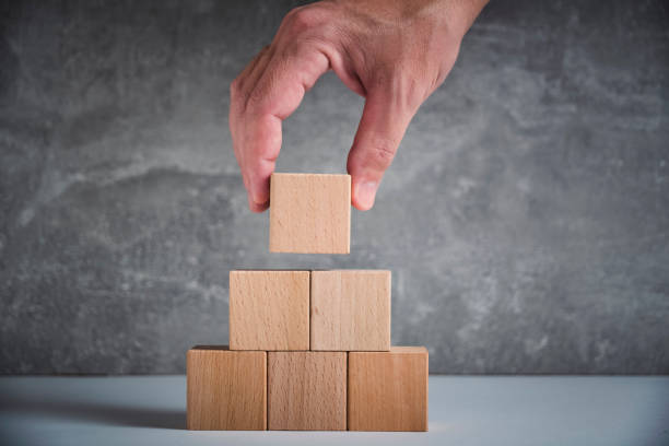 istock Laying out by hand a pyramid wooden cubes leading up.Concept growth and development. 1486183649