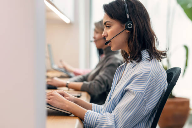 istock Group of female operator talking with wireless headset while searching information in laptop in the office 1486185087