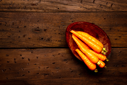 High angle view of carrots over rustic wood table in the kitchen  as healthy vegan food ingredients to prepare a salad at home