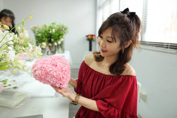 美しいアジアの花屋が母の日を祝うためにカーネーションのハート型の花束を持っています。 - carnation mothers day florist flower ストックフォトと画像