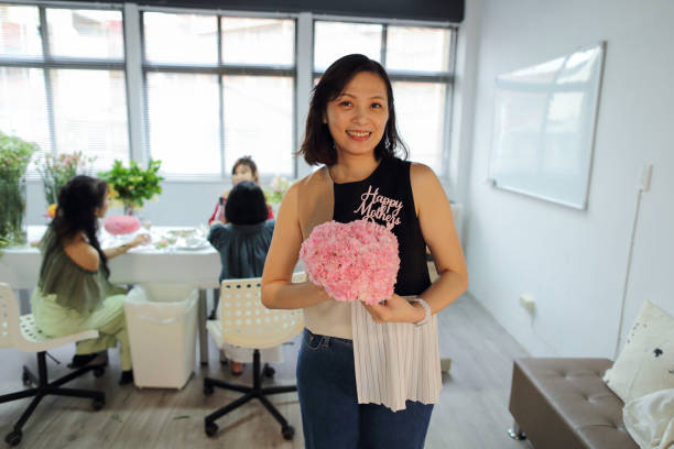 美しいアジアの花屋が母の日を祝うためにカーネーションのハート型の花束を持っています。 - carnation mothers day florist flower ストックフォトと画像