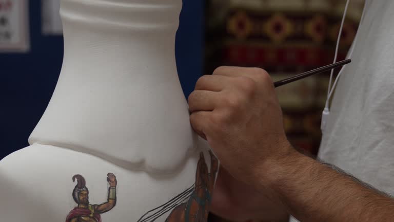 Closeup shot of a man painting a cup in his small crafts workshop