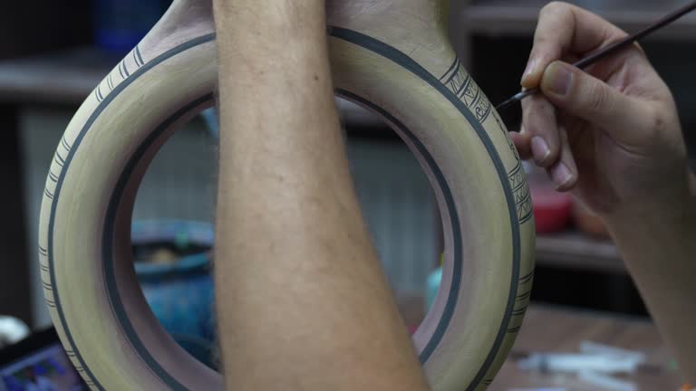 Closeup shot of a man painting a cup in his small crafts workshop