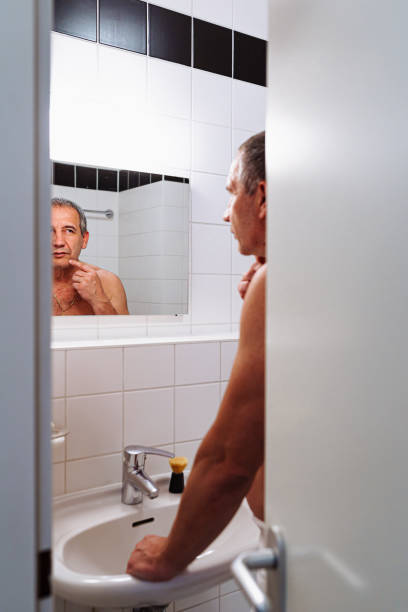istock middle-aged man looking in mirror in bathroom 1486208376