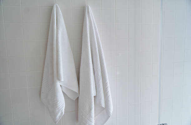 due asciugamani bianchi appesi nella doccia dell'hotel - towel hanging bathroom railing foto e immagini stock