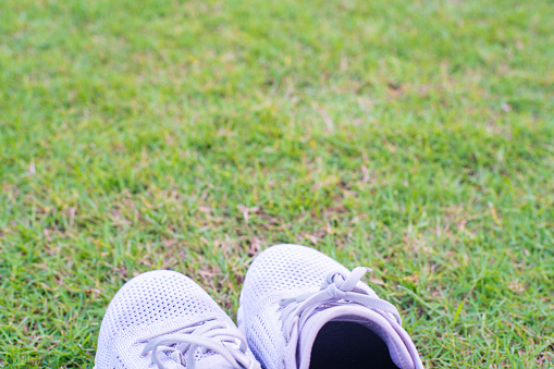 White running shoe on green football grass field sport object