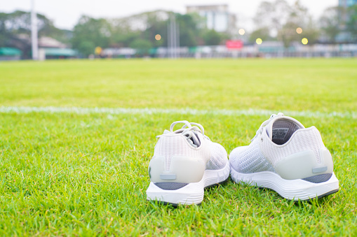 White running shoe on green football grass field sport object