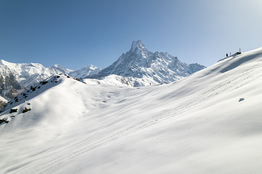 The snow-clad mountain slope is a pristine and tranquil sight to behold. The glistening white snow blankets the rugged terrain, creating a serene and ethereal landscape that invites adventure and serenity