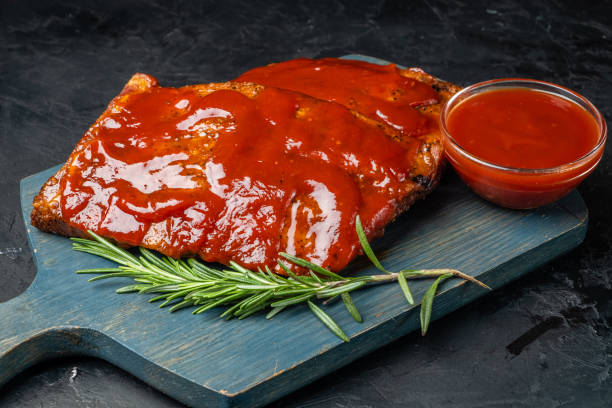 istock Appetizing grilled pork ribs served on a board. Dark background. 1486229562