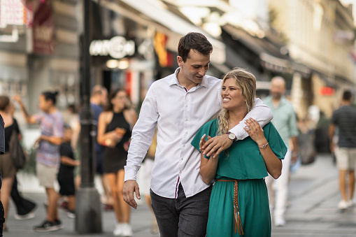 A shot of heterosexual couple in love walking in the city and smiling