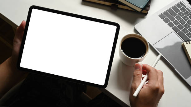istock Close up view of young man using digital tablet with blank empty mockup screen at white working desk. 1486231843