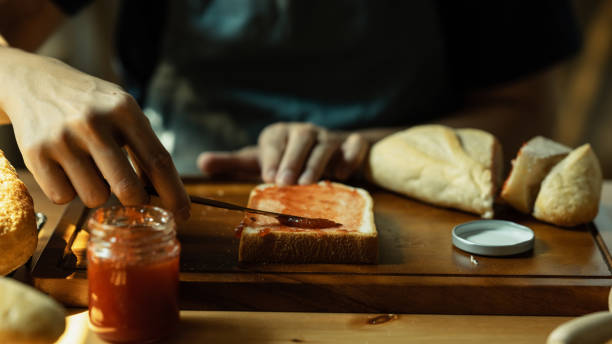 istock Man spreading sweet raspberry jam on bread during for breakfast or brunch in kitchen. Cropped shot. 1486231903