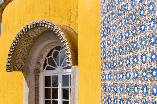 Sintra, Portugal-October 2023: Close up view of part of the yellow facade and colorful tiles with window of the Pena National Palace