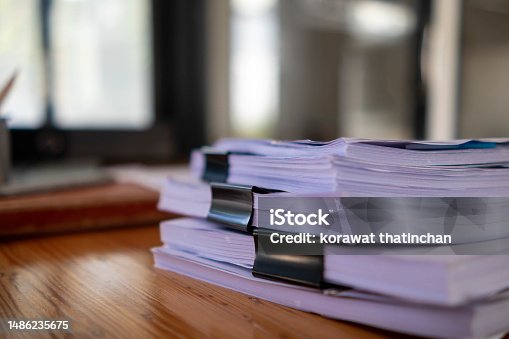 istock Businesswoman hands working on stacks of paper documents to search and review documents piled on table before sending them to board of directors to use  correct documents in meeting with Businessman 1486235675