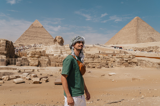 Female photographer in vacation standing with photo camera in front of the great pyramids. Egypt, Cairo - Giza