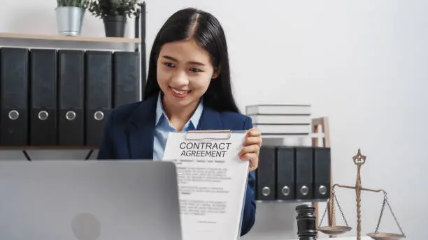 Photo of Young single female lawyer asian people in formal suit real estate working law book and contract documents, Arguments for Defense Strategy. Fight for Freedom. Supporting Evidence.