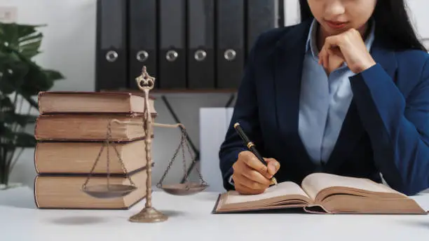 Photo of Young single female lawyer asian people in formal suit real estate working law book and contract documents, Arguments for Defense Strategy. Fight for Freedom. Supporting Evidence.