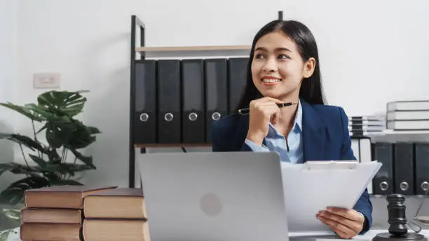 Photo of Young single female lawyer asian people in formal suit real estate working law book and contract documents, Arguments for Defense Strategy. Fight for Freedom. Supporting Evidence.