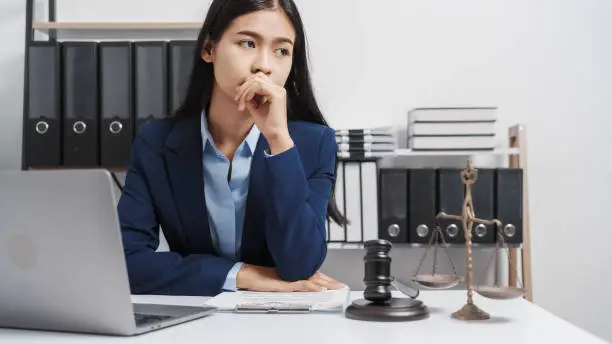 Photo of Young single female lawyer asian people in formal suit real estate working law book and contract documents, Arguments for Defense Strategy. Fight for Freedom. Supporting Evidence.