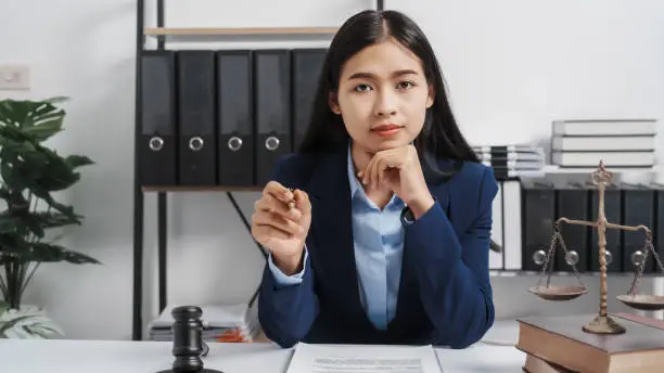 Photo of Young single female lawyer asian people in formal suit real estate working law book and contract documents, Arguments for Defense Strategy. Fight for Freedom. Supporting Evidence.