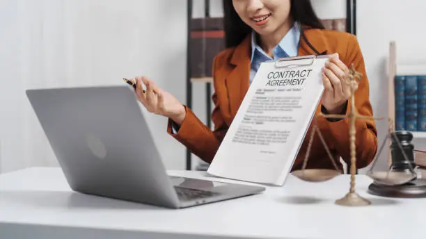 Photo of Young single female lawyer asian people in formal suit real estate working law book and contract documents, Arguments for Defense Strategy. Fight for Freedom. Supporting Evidence.